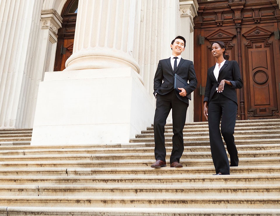 two municipal workers walking down stairs of a government building smiling and talking